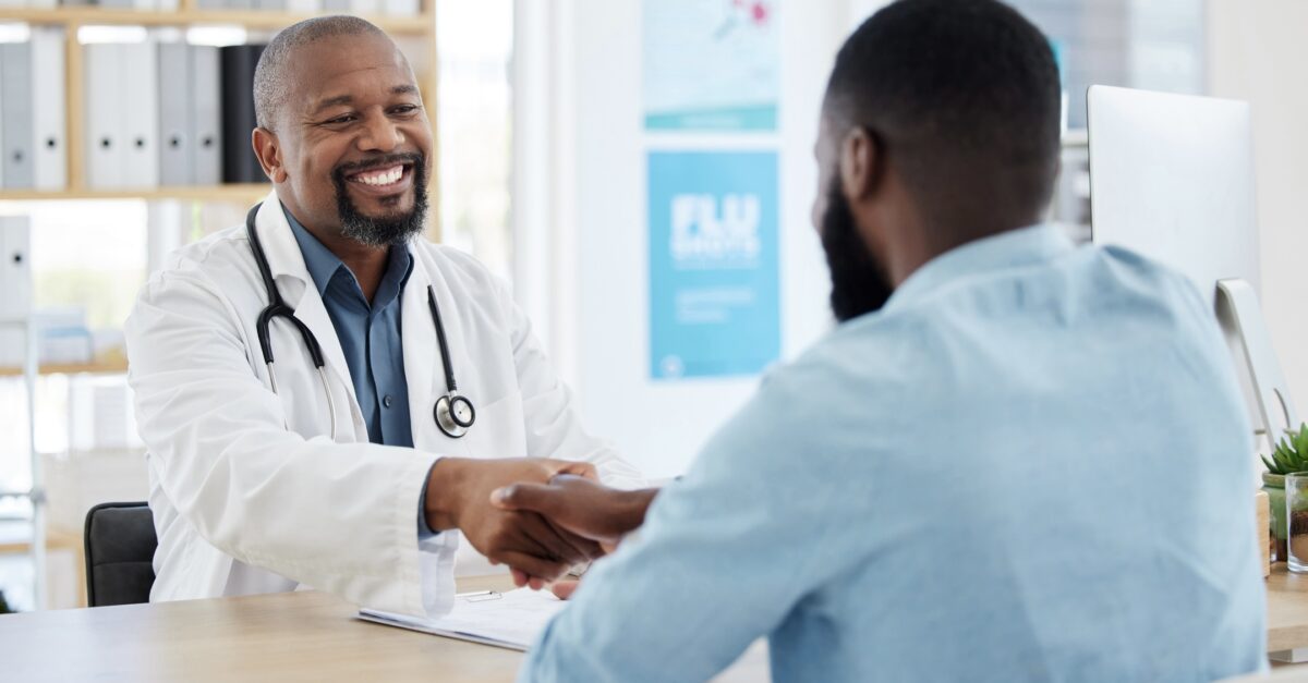 Happy doctor greeting his patient with a handshake.